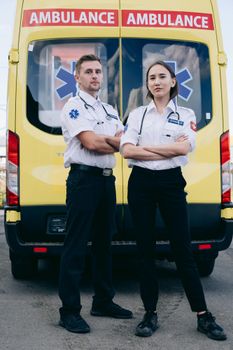 Two paramedics confidently stand in front of a yellow ambulance, showcasing teamwork and readiness.