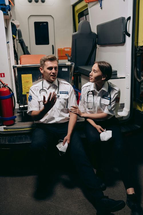 Free Two paramedics in uniform sit in an ambulance discussing their work, fostering teamwork. Stock Photo
