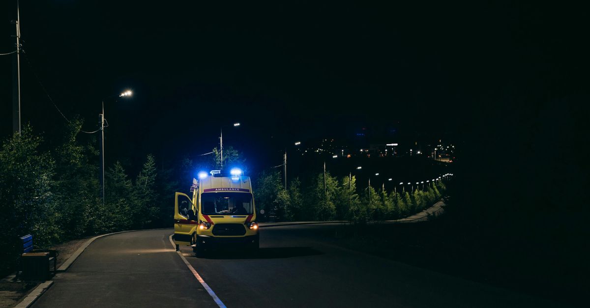 Ambulance with flashing lights on a rural road at night, ready for emergency response.