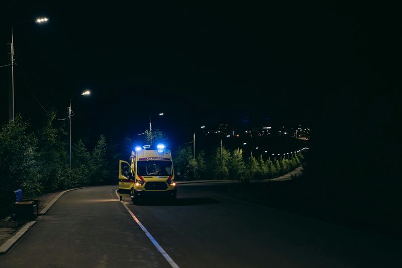 Roadside assistance operator providing a jump start at night