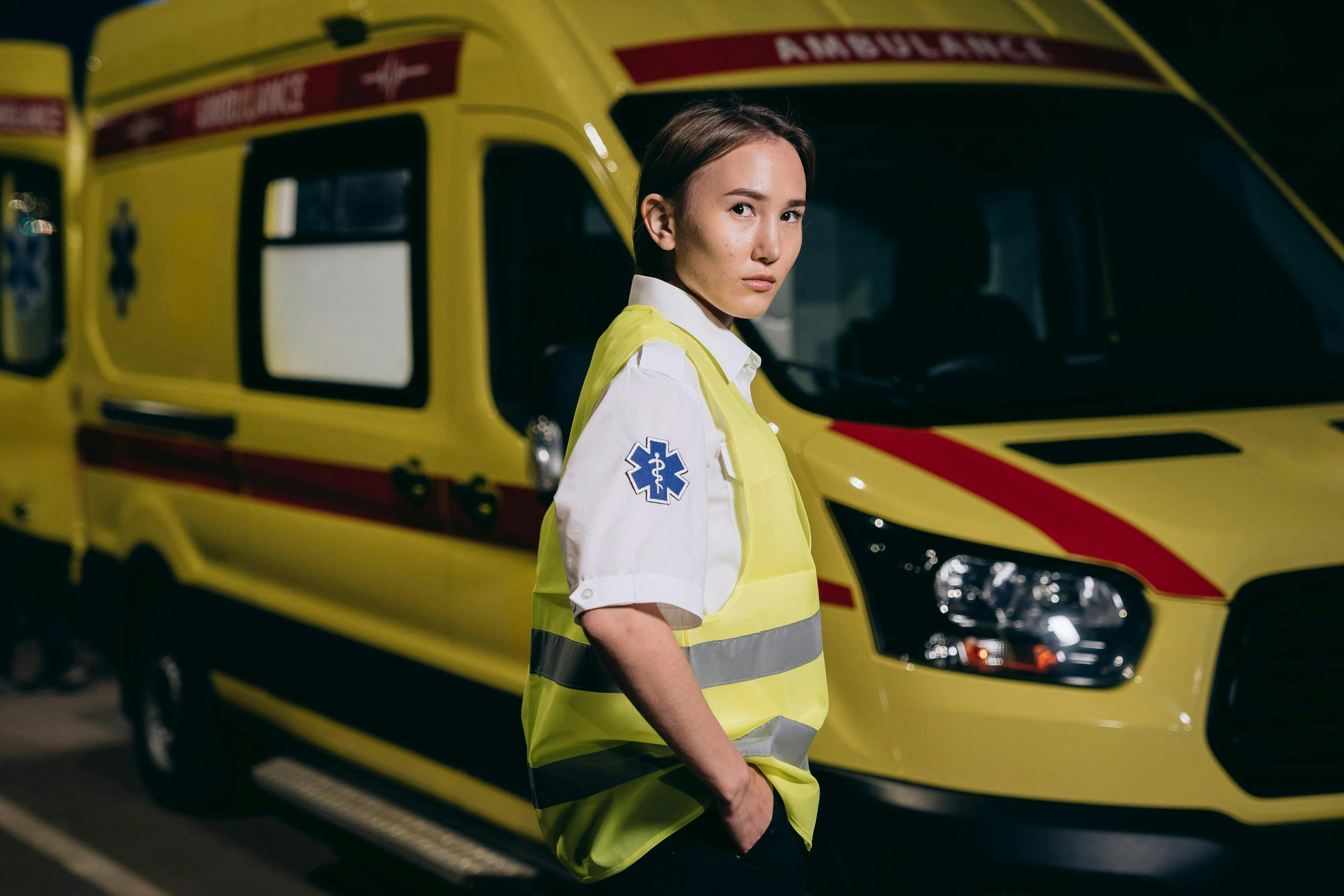 paramedic in a reflective vest by the yellow ambulance