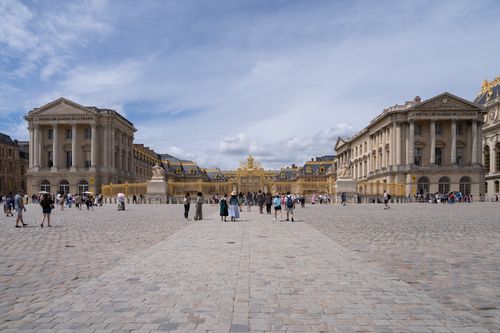 Free Tourists walk through the grand courtyard of the historic Palace of Versailles in France. Stock Photo