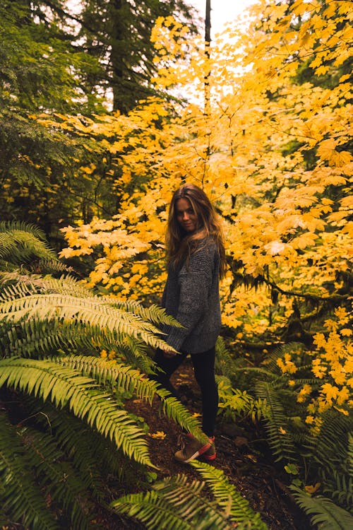 Фотография женщины, стоящей возле желтых растений