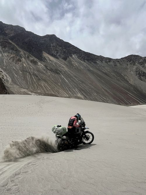 Free Motorcyclists tackling a sandy trail in a dramatic mountainous desert scene. Stock Photo