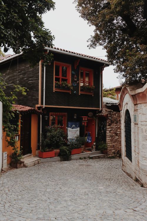 Free A picturesque rustic house on a cobblestone street, featuring vibrant colors and lush greenery. Stock Photo
