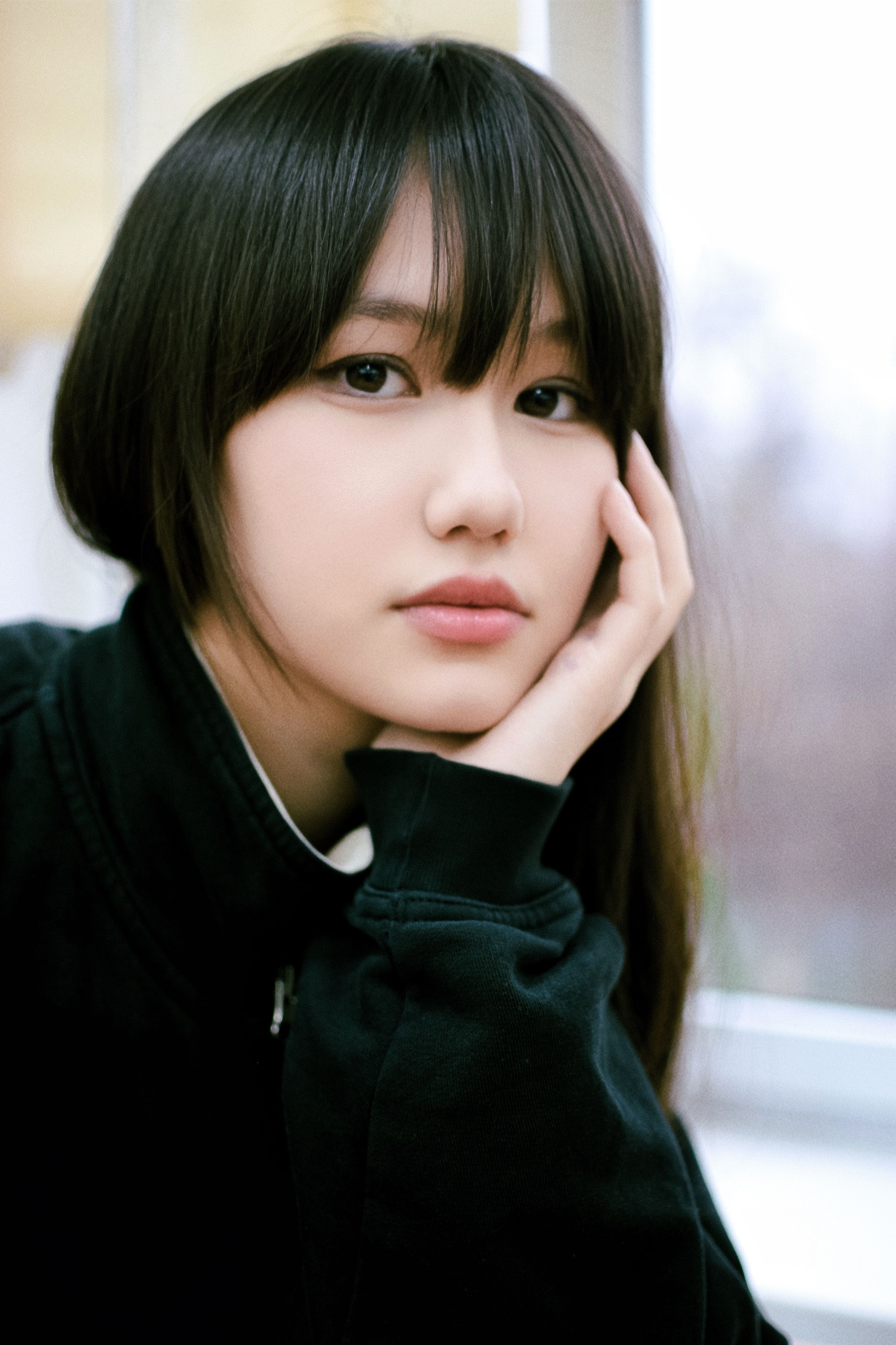 Portrait of a young woman with a pensive gaze, elegantly posed indoors.