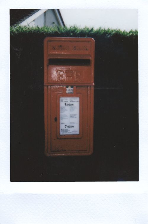 Free Classic red mailbox with retro appeal captured on instant film in an outdoor setting. Stock Photo