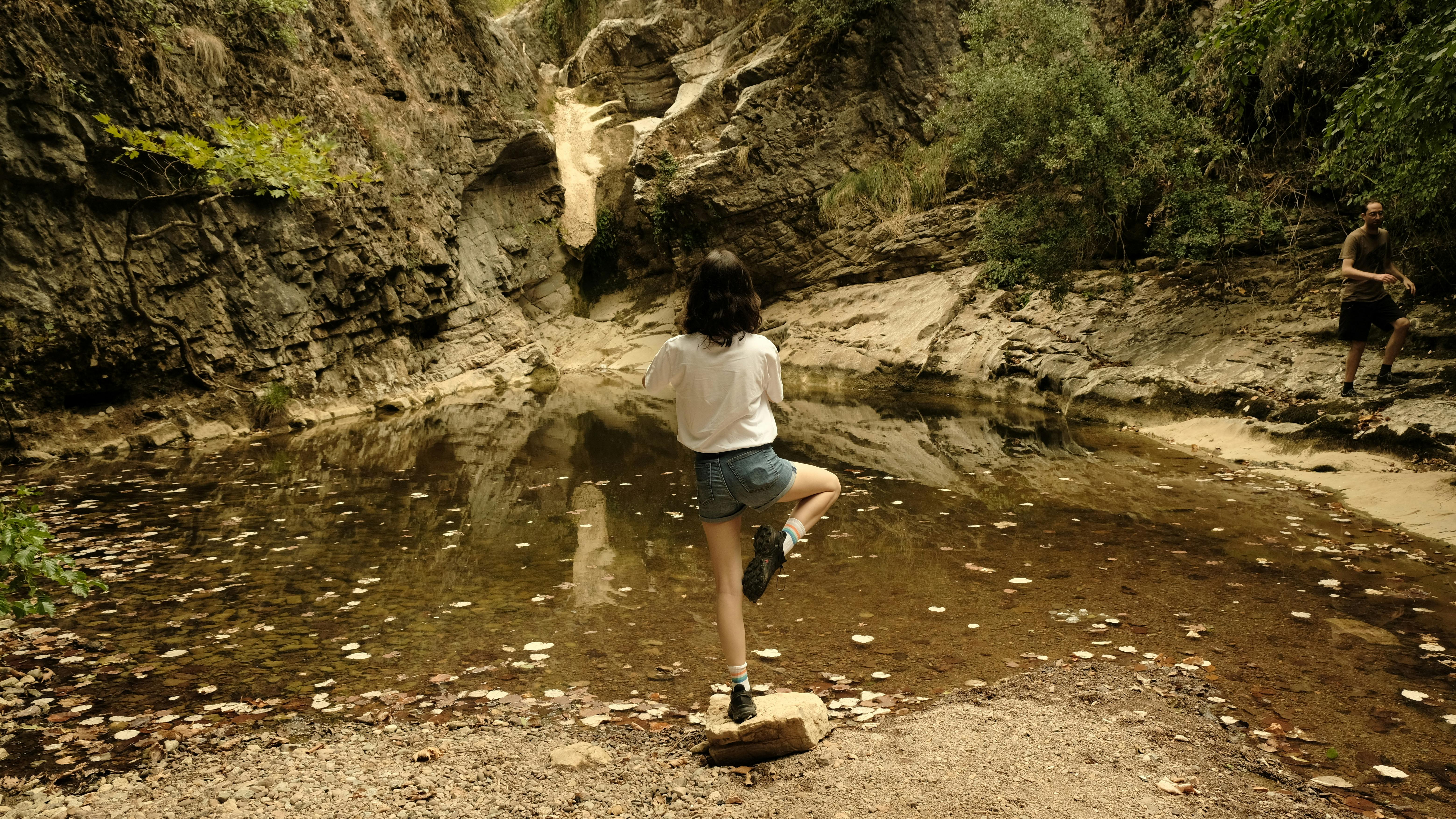 a woman standing on a rock in a small pond