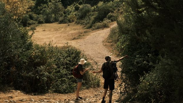 Two young adults enjoying a hiking adventure in a lush forest during daytime.