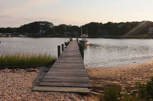 Free Serene wooden pier at sunset in Hampton Bays, NY, leading to calm waters. Stock Photo