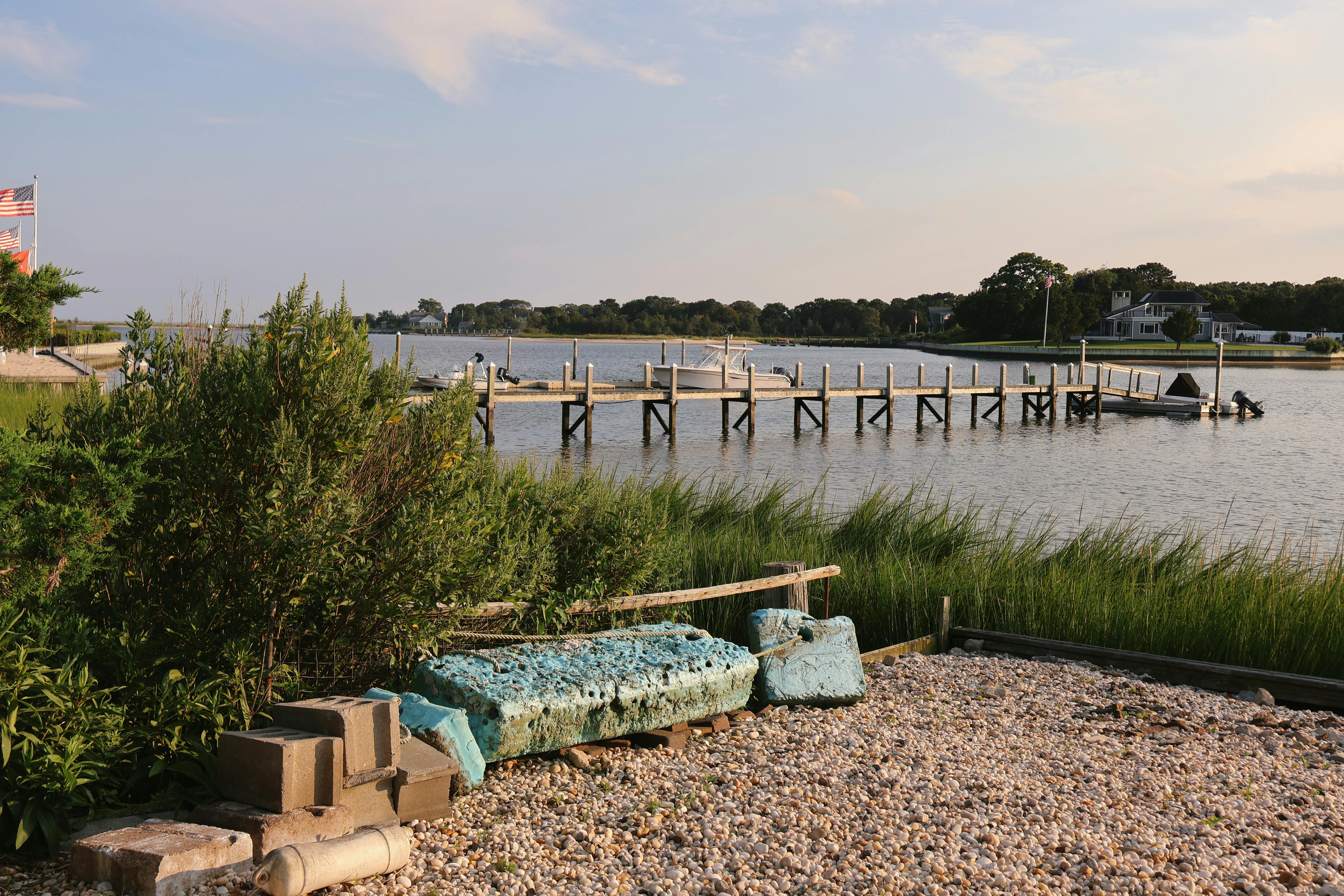 a bench is sitting on the shore next to a dock