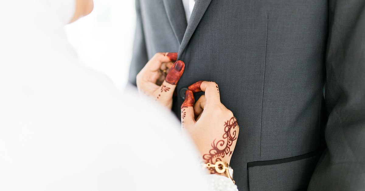Close-up of hands adjusting groom's suit, showcasing elegant wedding attire and togetherness.