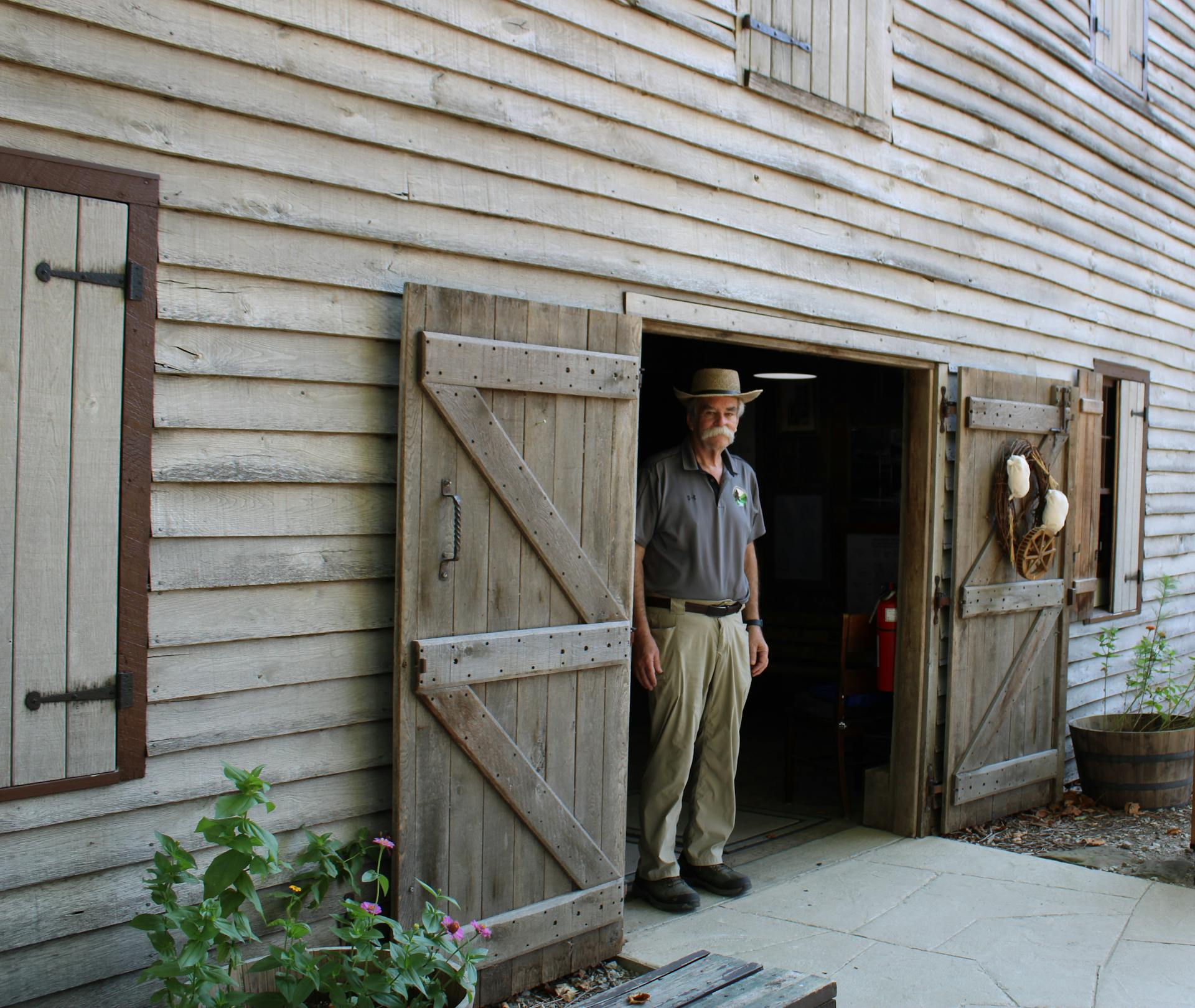 Historian At Restored Grain Mill Standing In Doorway