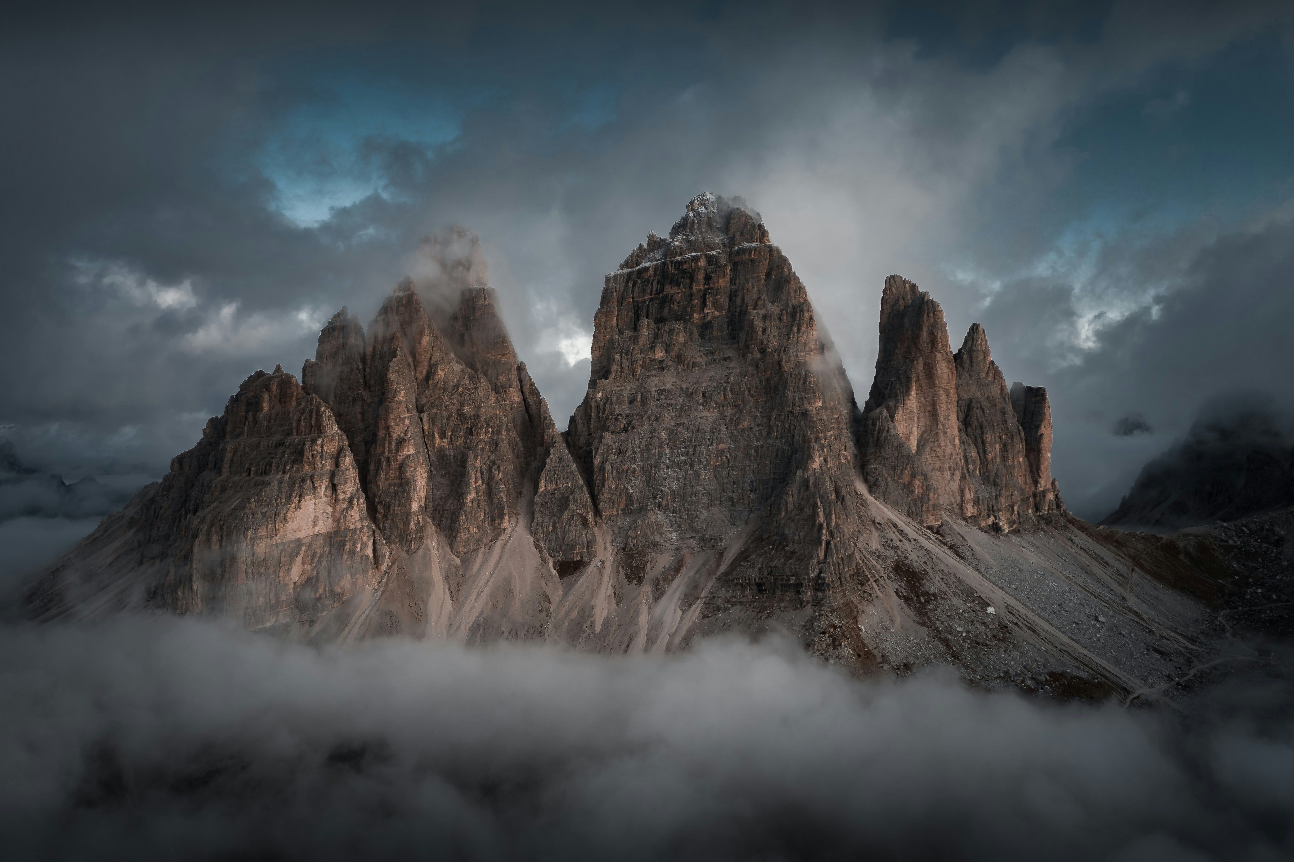 Dramatic mountain range piercing through foggy clouds, creating a breathtaking landscape.