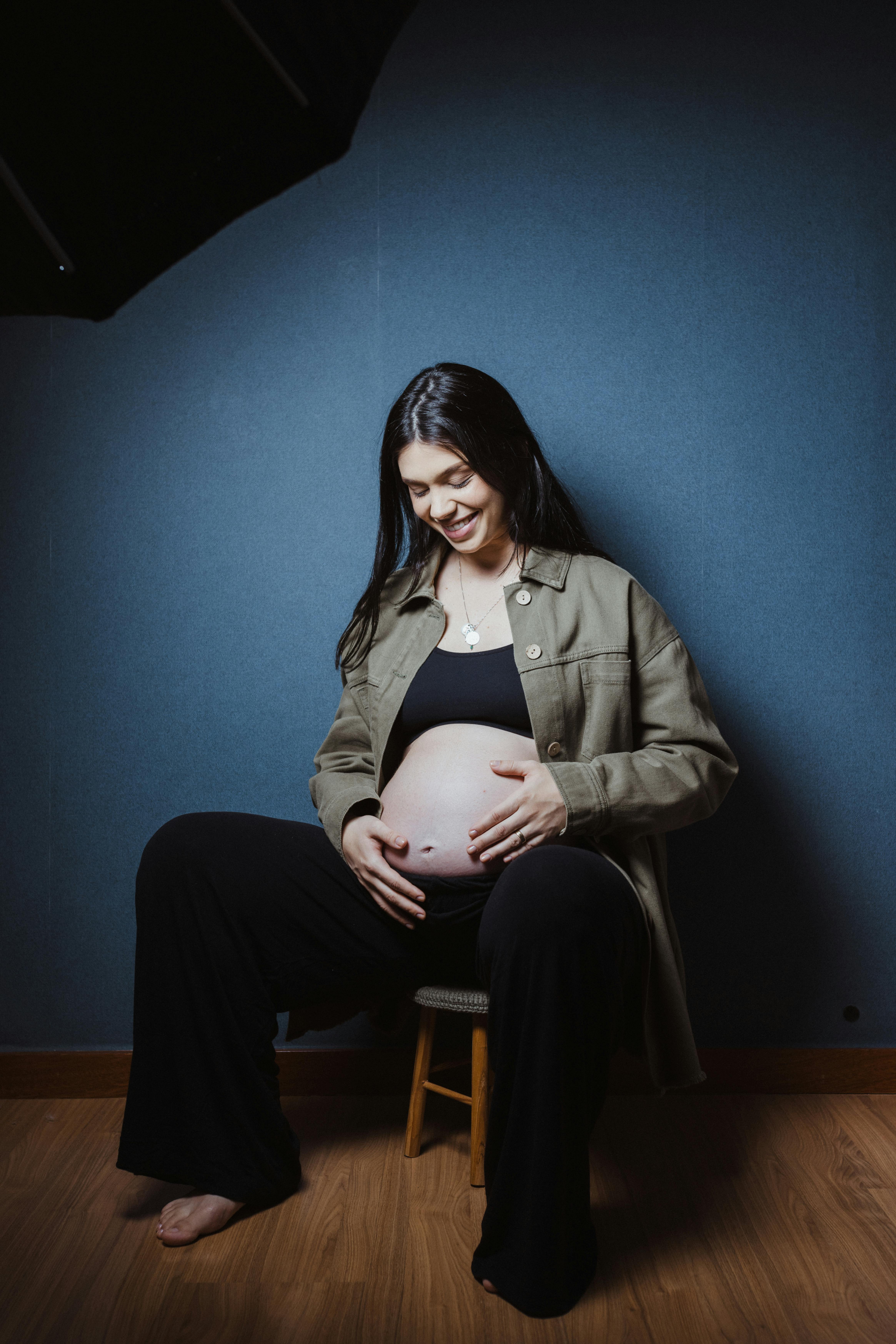 a pregnant woman sitting on a chair with an umbrella