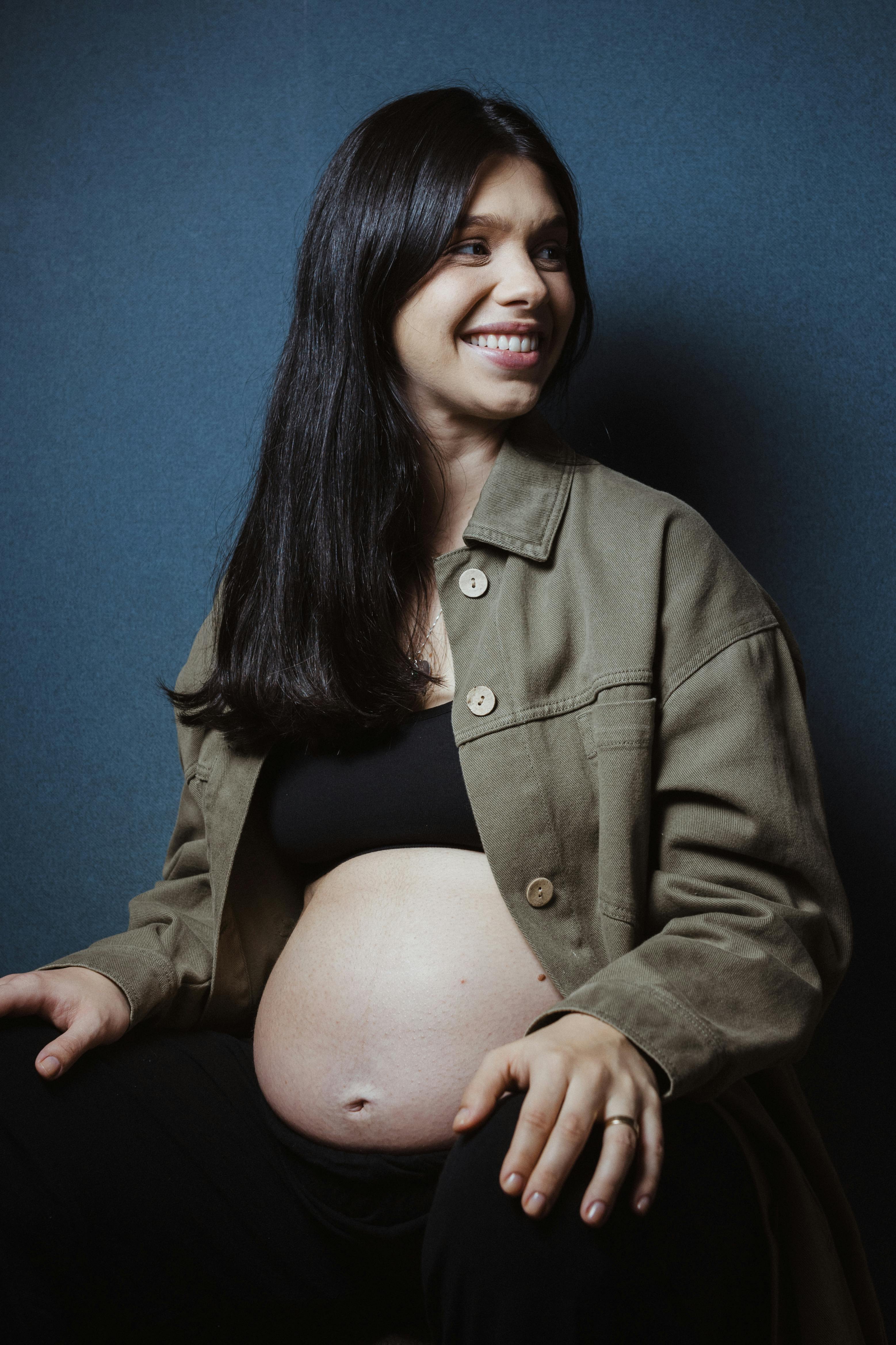 a pregnant woman in a black jacket and jeans