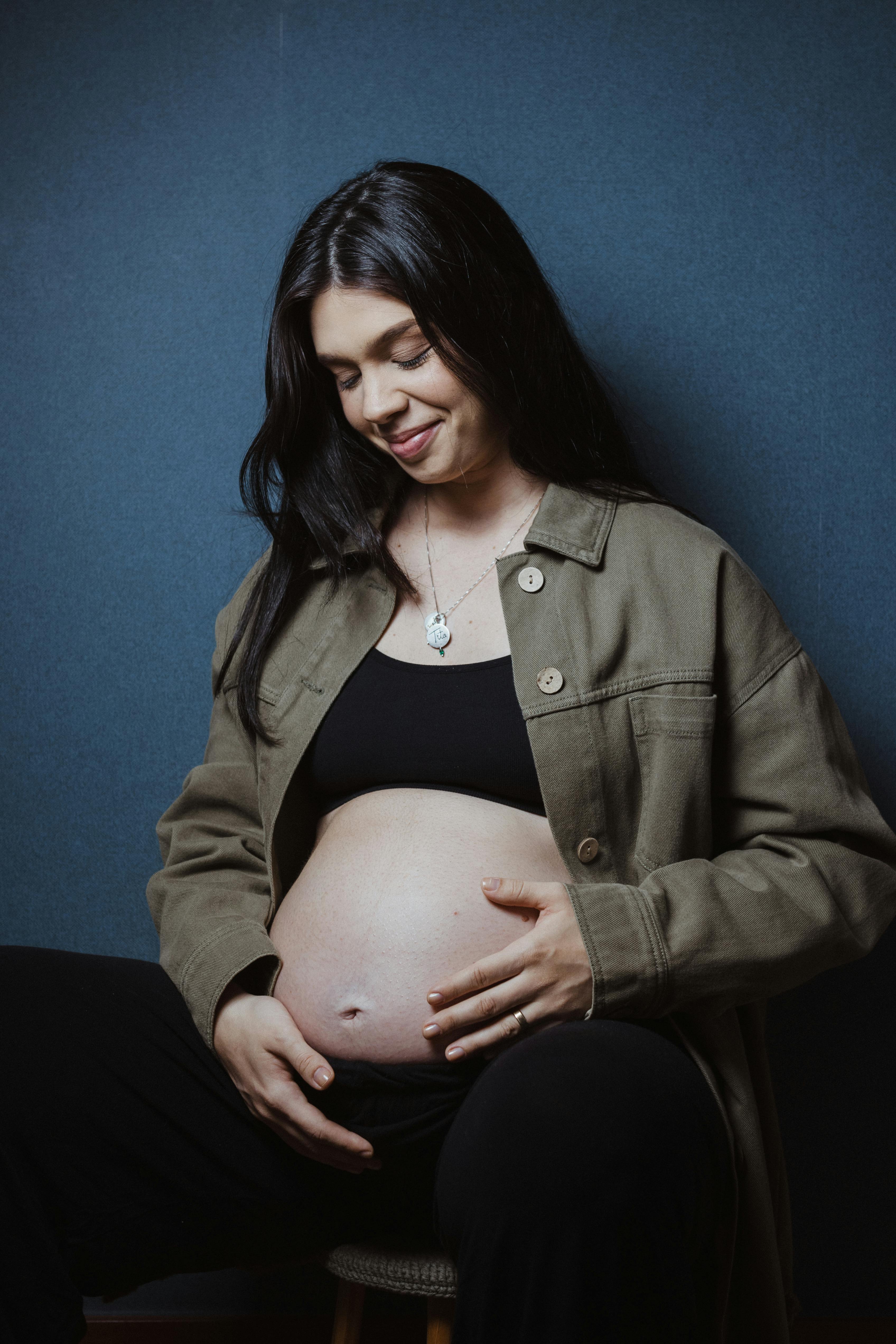 a pregnant woman is sitting on a stool and smiling