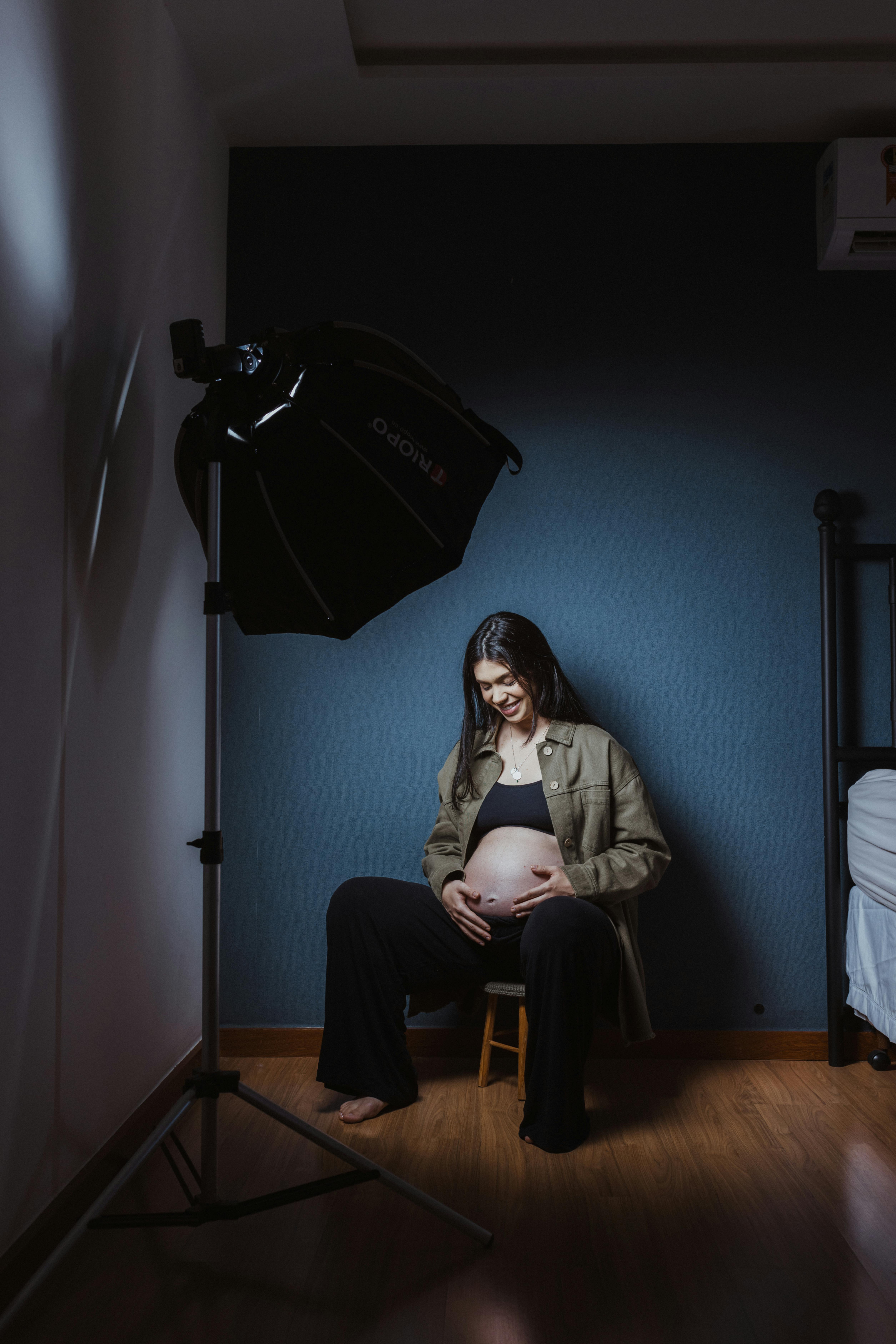 a pregnant woman sitting in a room with a light