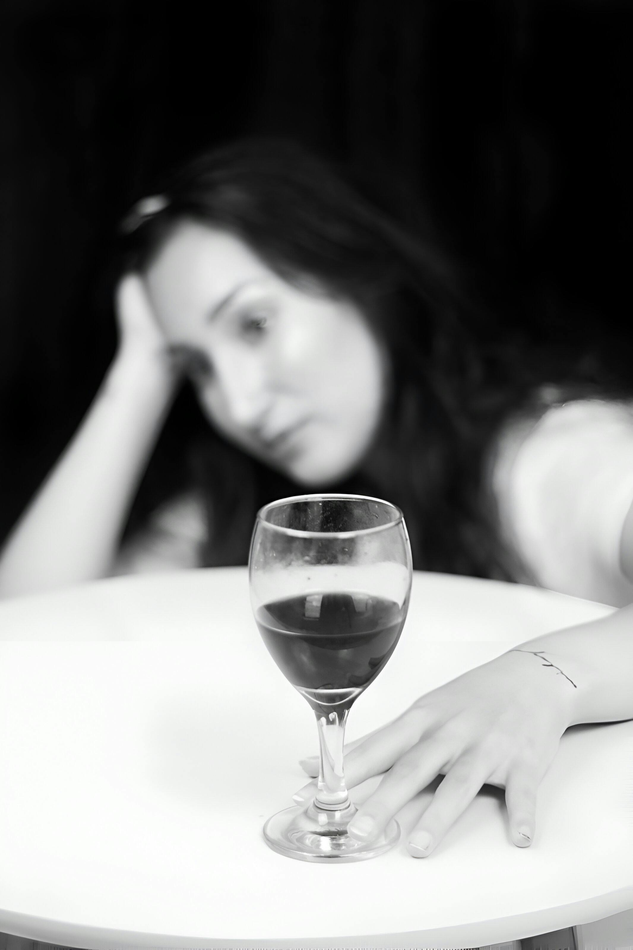 a woman sitting at a table with a glass of wine