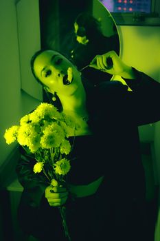 Dramatic green-toned portrait of a woman holding flowers in a reflective room.