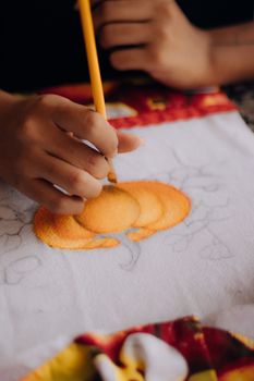 Close-up of a hand artistically painting a vibrant fruit design on fabric. Ideal for creative and art-related projects.