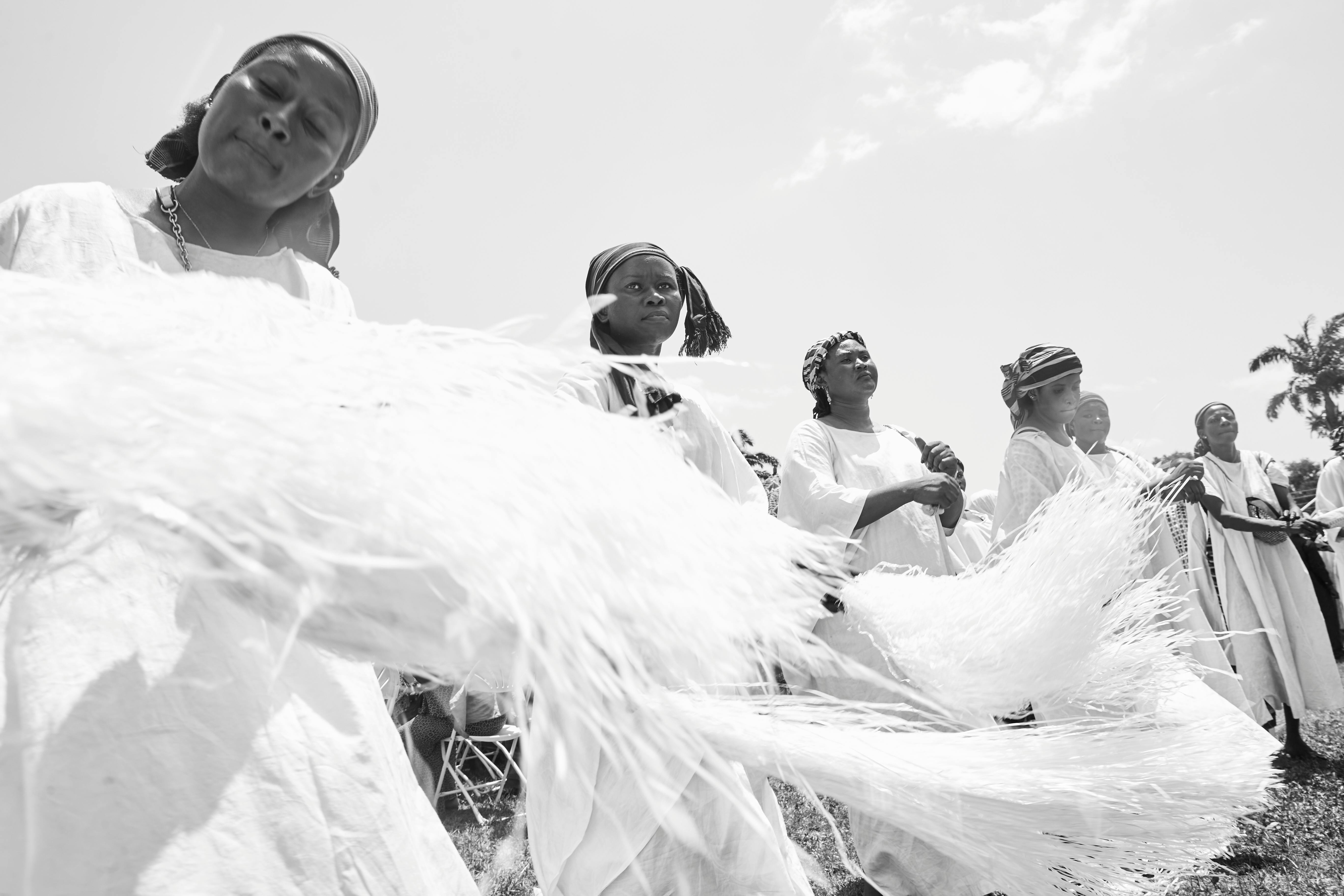 Group of adults in traditional attire performing a cultural dance outdoors.