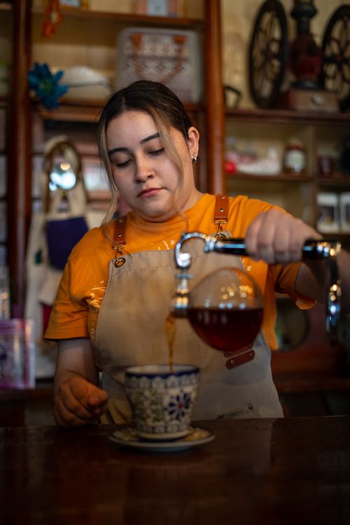 Free A barista pouring gourmet coffee into a ceramic cup at a cozy café. Stock Photo