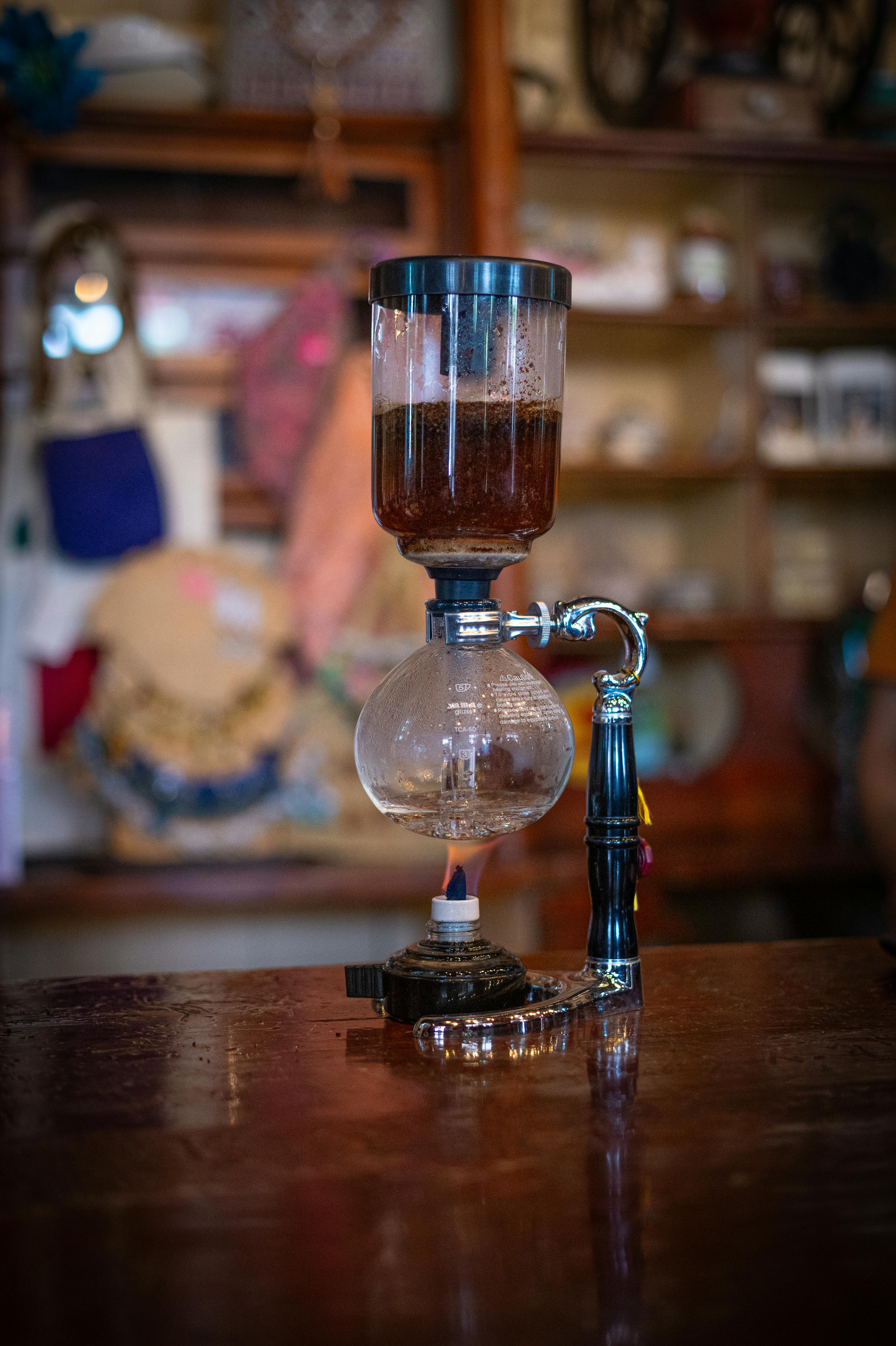Siphon coffee maker brewing in a cozy café with a rustic interior.