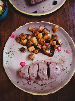 Gourmet dish of meat and roasted potatoes on a rustic plate, perfect for dinner ideas.