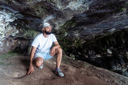 A man wearing casual attire explores a rocky cave in Gagra, showcasing adventure and travel vibes.