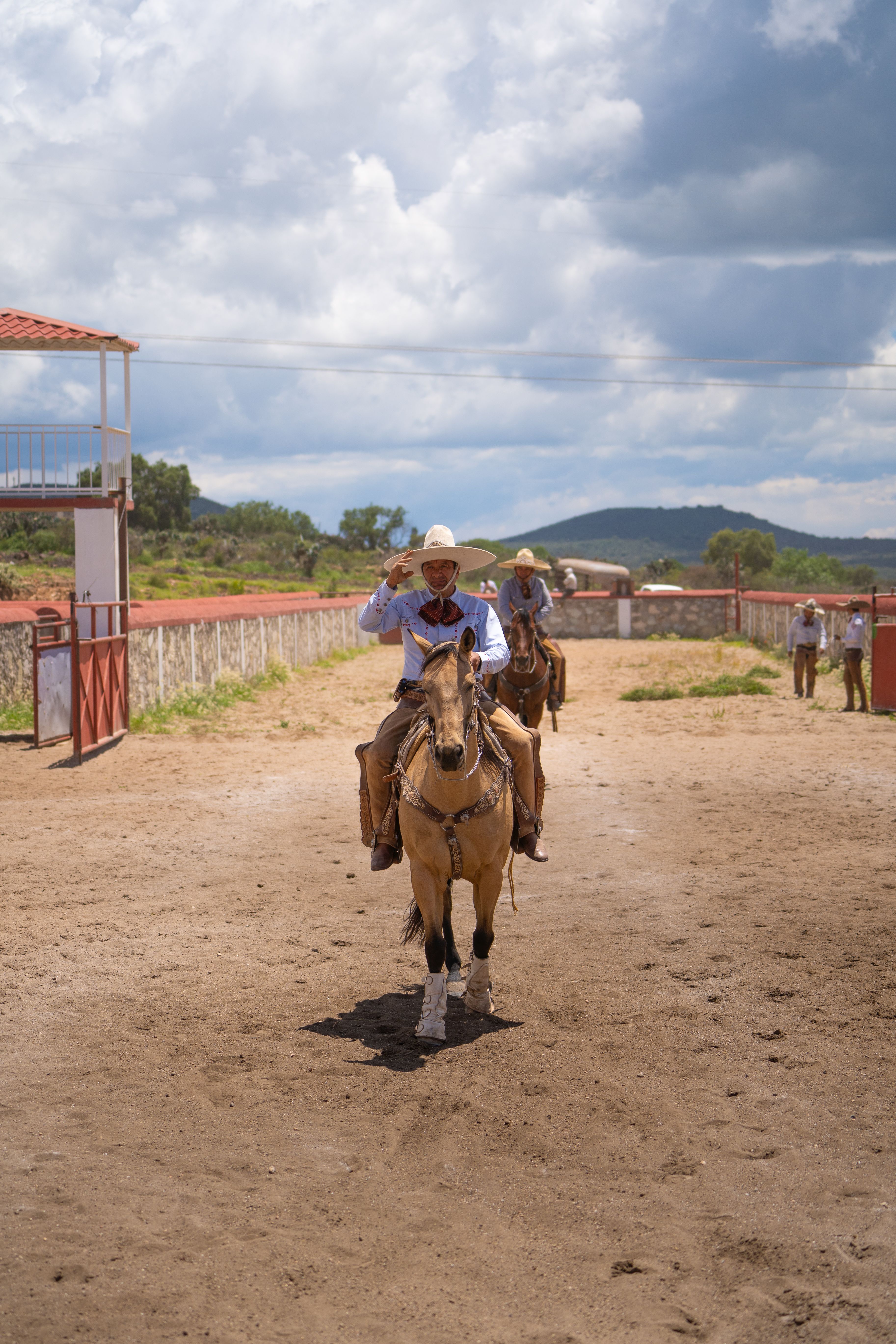 Charros ride horses in a Mexican arena showcasing traditional culture.
