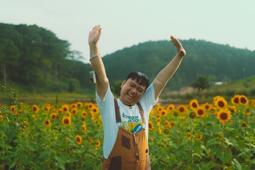 A cheerful person enjoying the sunflower bloom in Dalat, Vietnam, expressing vibrant happiness.