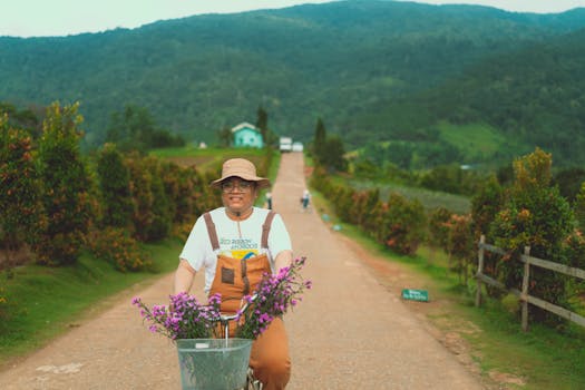 A person rides a bicycle with purple flowers along a scenic road in Dalat, Vietnam.