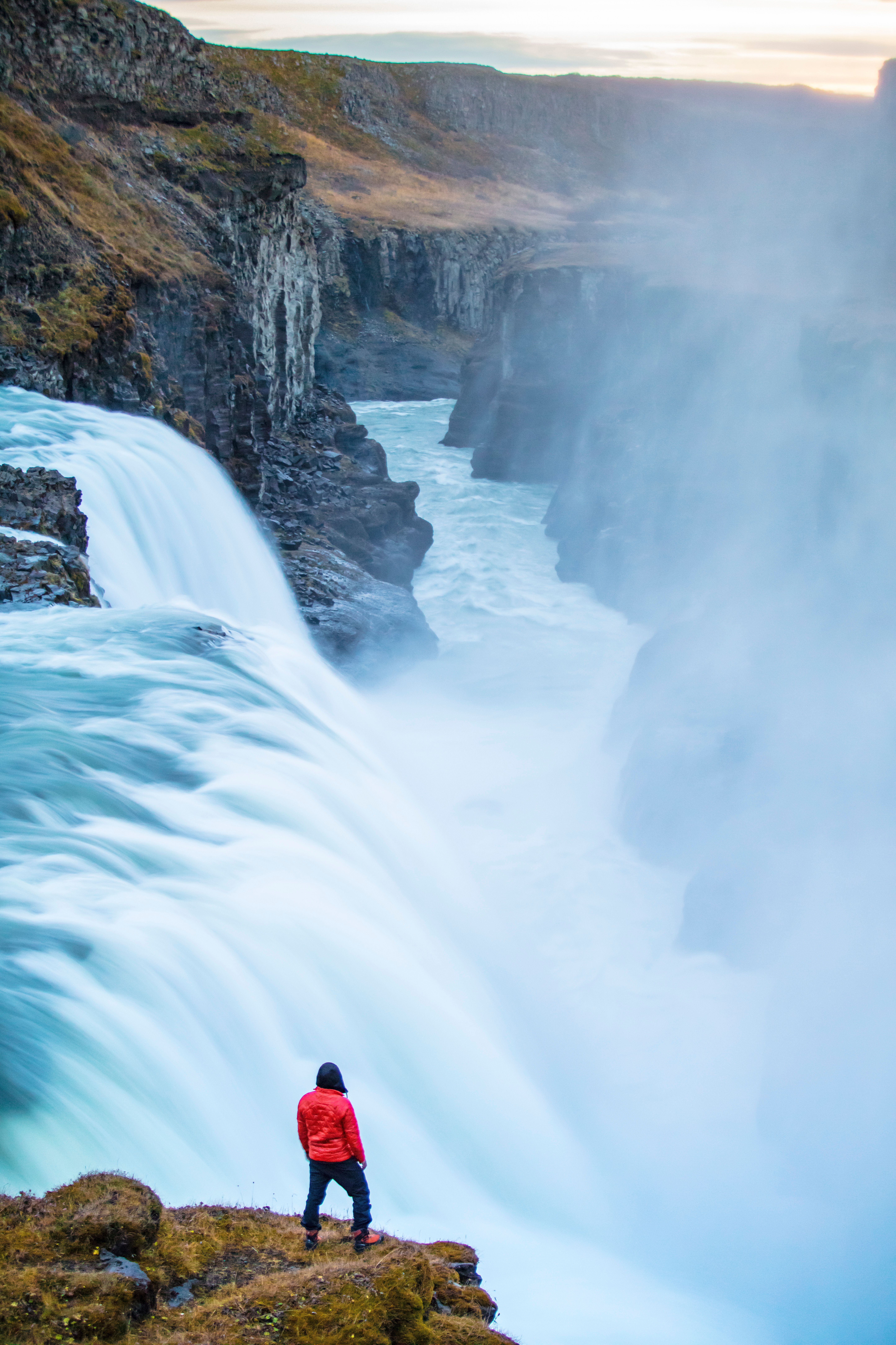 A person standing on the edge of a waterfall · Free Stock Photo