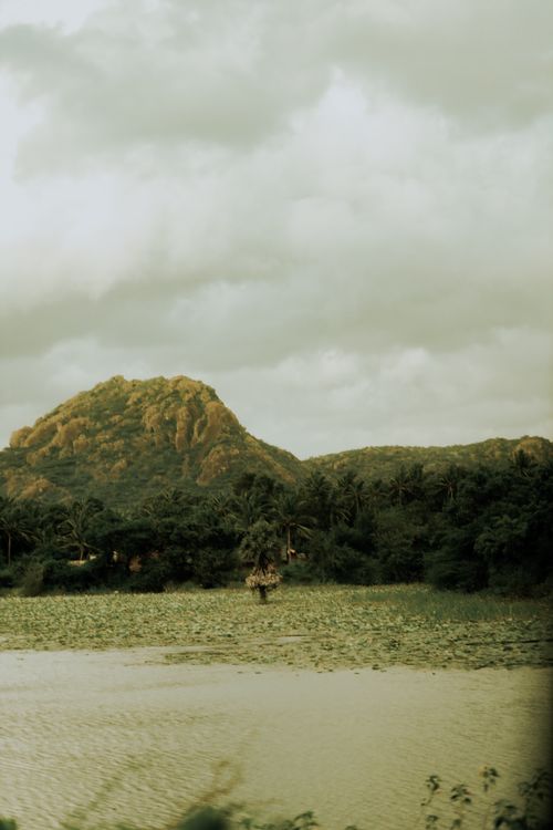Free Serene landscape featuring a mountain surrounded by dense greenery and a tranquil lake. Stock Photo
