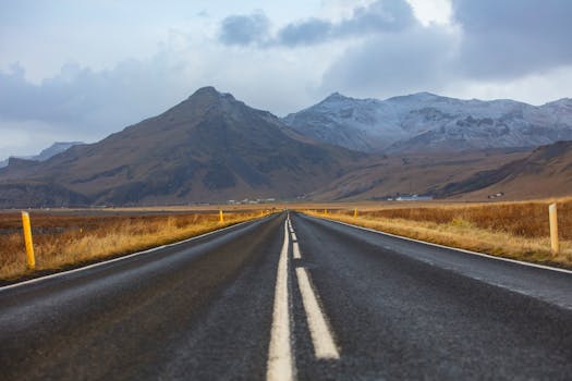 A long, empty road through a stunning mountain landscape in autumn, ideal for travel themes.