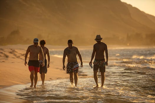 Four men walk along the beach during sunset, enjoying a leisurely moment by the sea.