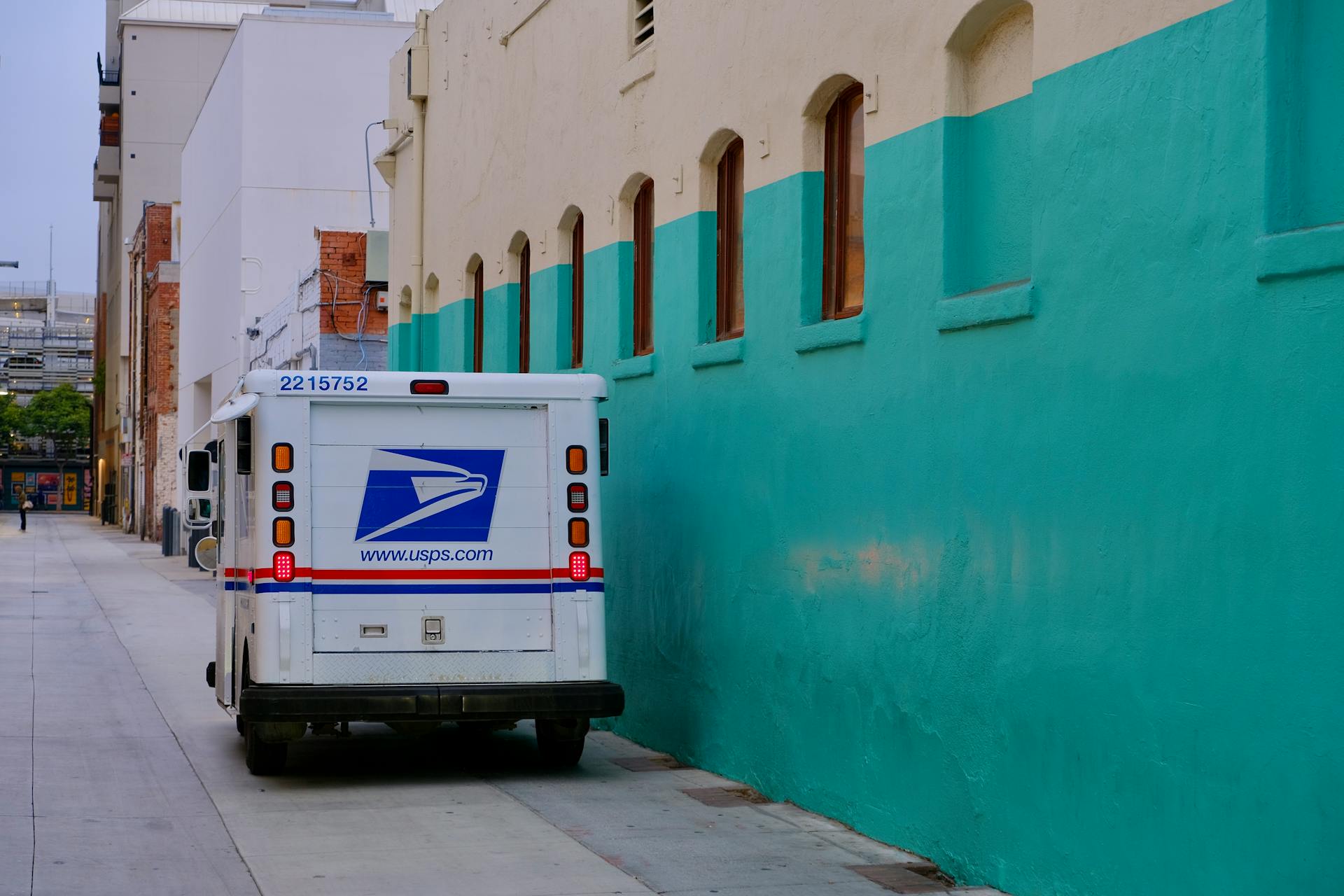 A white postal truck parked in front of a blue wall