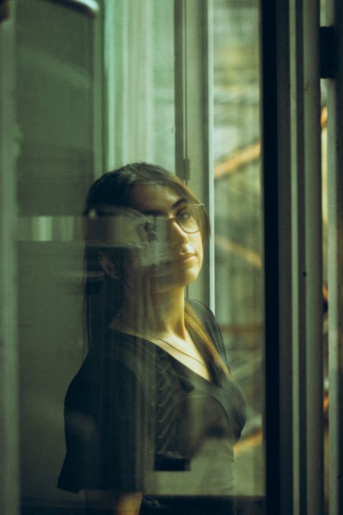 Free A pensive woman in Baku gazes through a window, capturing urban reflections. Stock Photo