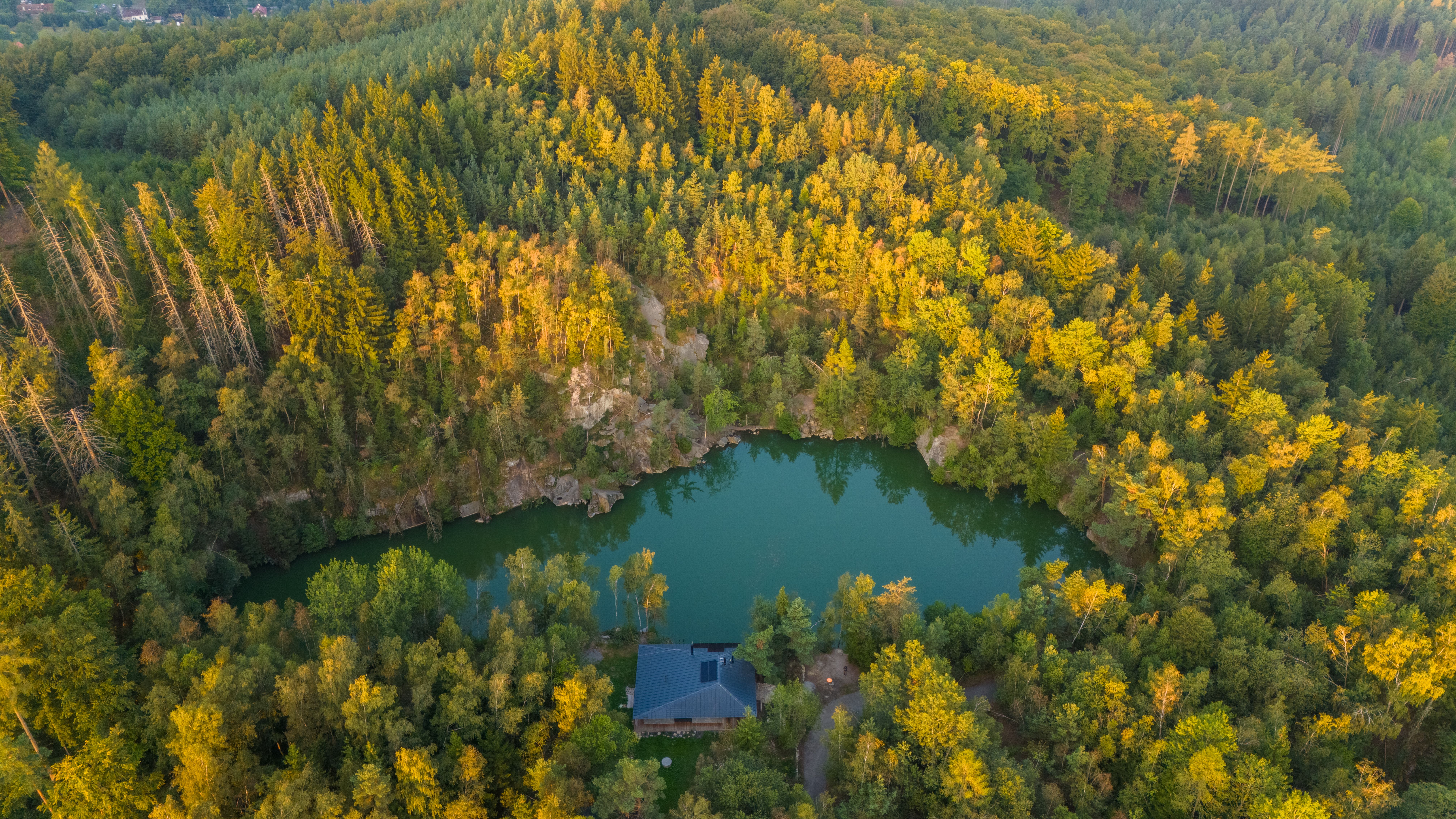 Stunning aerial view of a tranquil lake surrounded by dense forest in Havlíčkův Brod, Czechia.