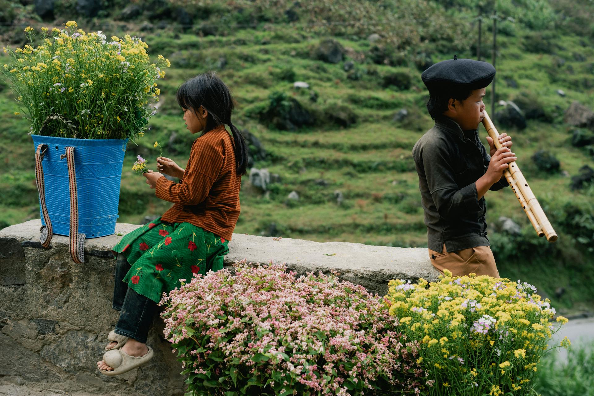 A Girl Picking Flowers and a Boy Playing an Instrument