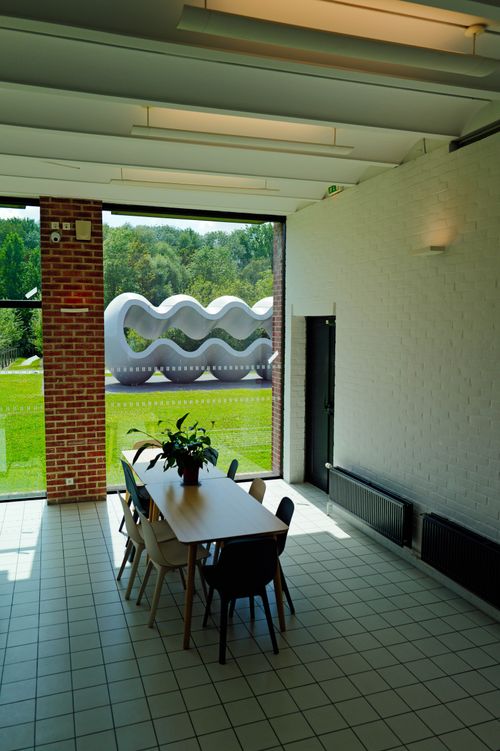 Free Bright contemporary meeting room with large window views of an abstract outdoor sculpture and lush greenery. Stock Photo