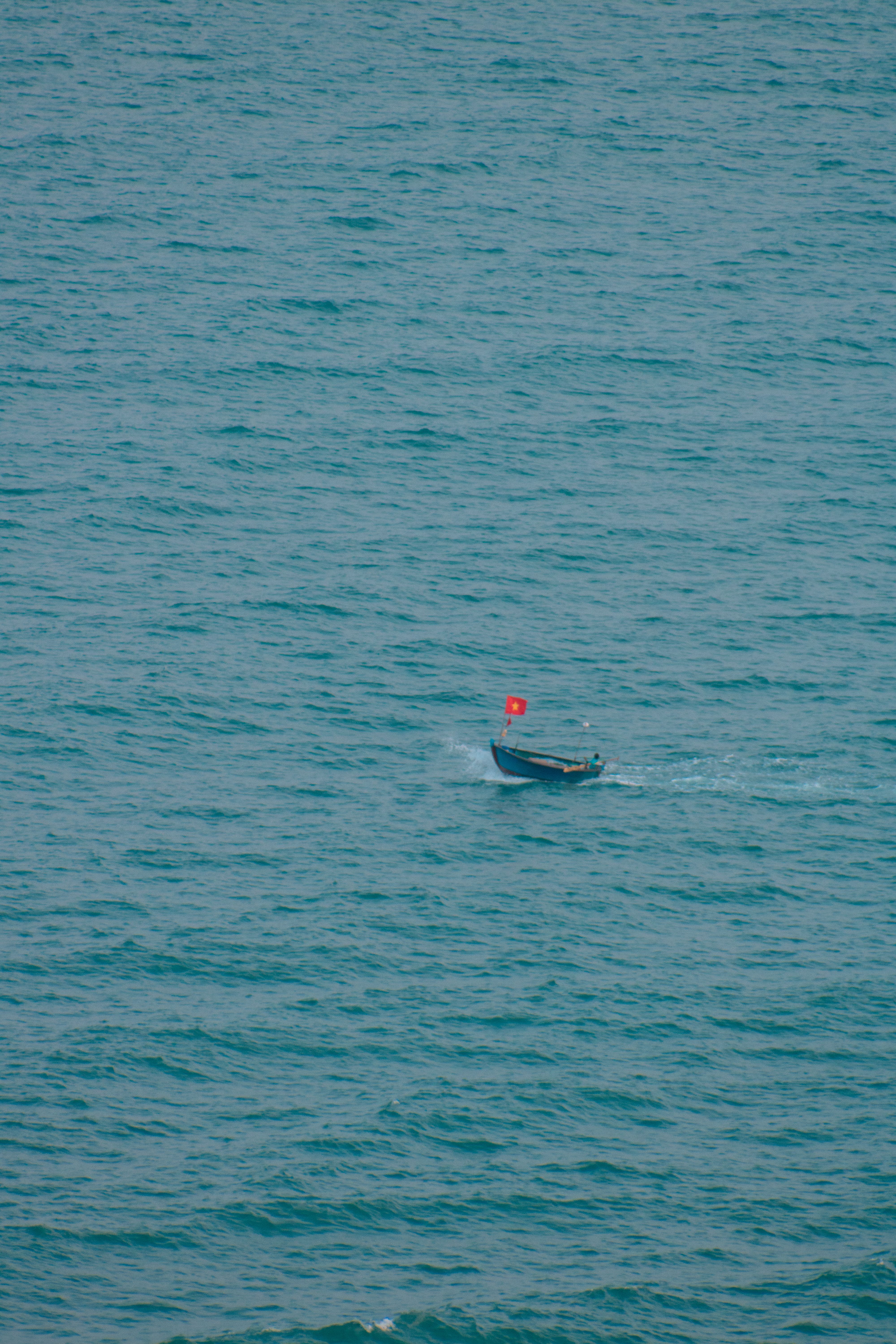 A serene view of a fishing boat with a red flag on the sea in Da Nang, Vietnam.