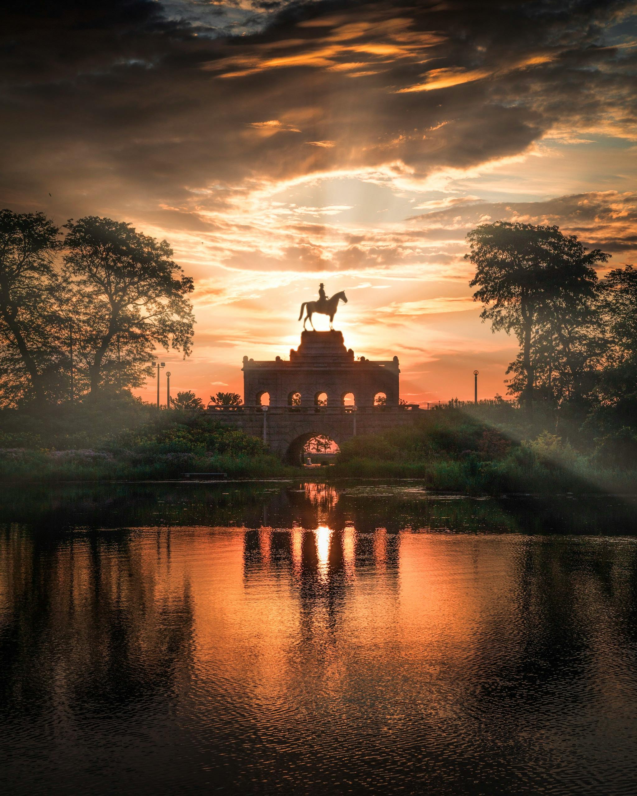 马术雕像的轮廓在充满活力的日落和水面倒影映衬下，显得格外令人惊叹