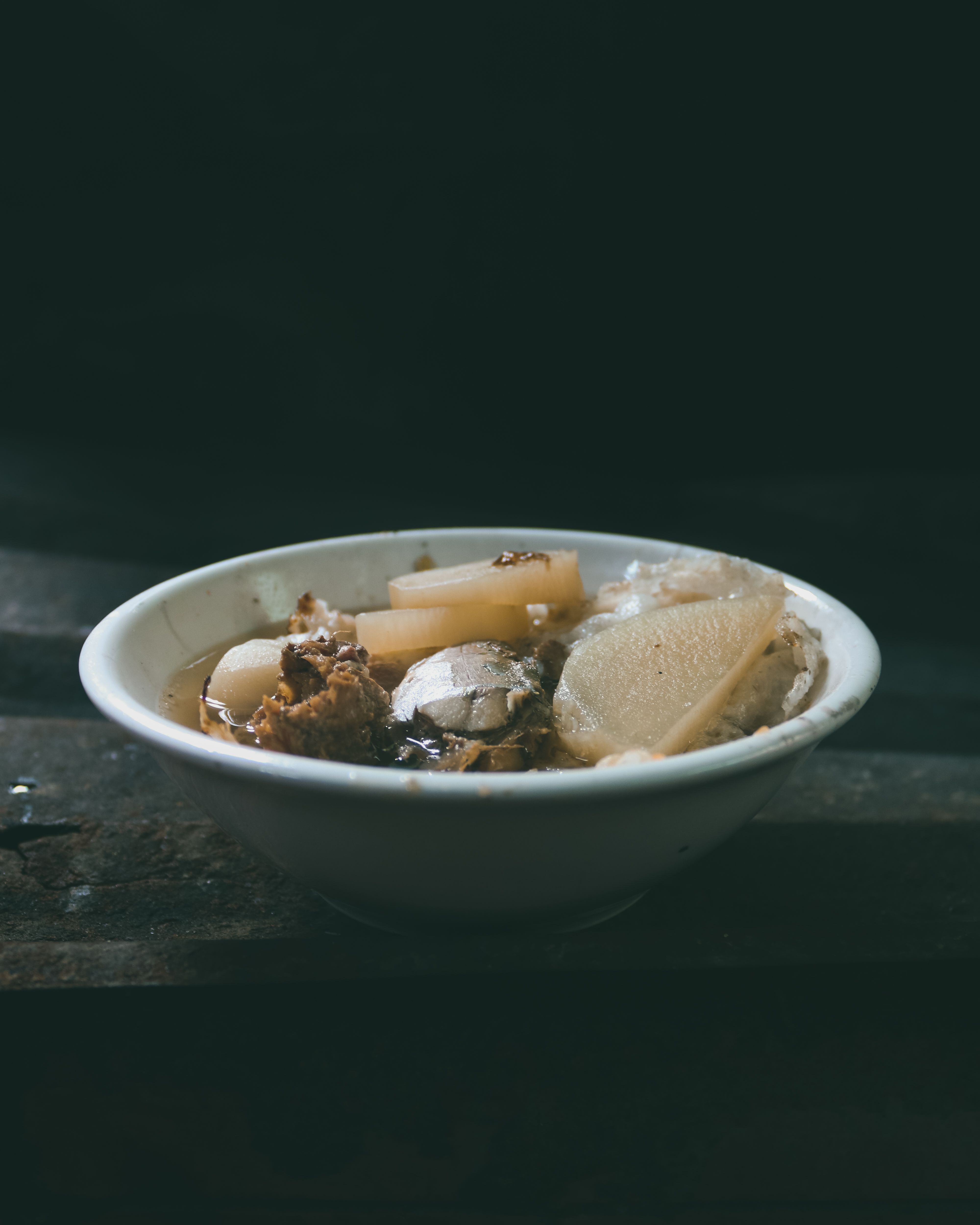 A bowl of traditional Vietnamese mushroom soup with hearty ingredients on a rustic wooden table.