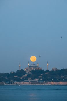 Stunning view of the full moon rising over Hagia Sophia Mosque, Istanbul at dusk.