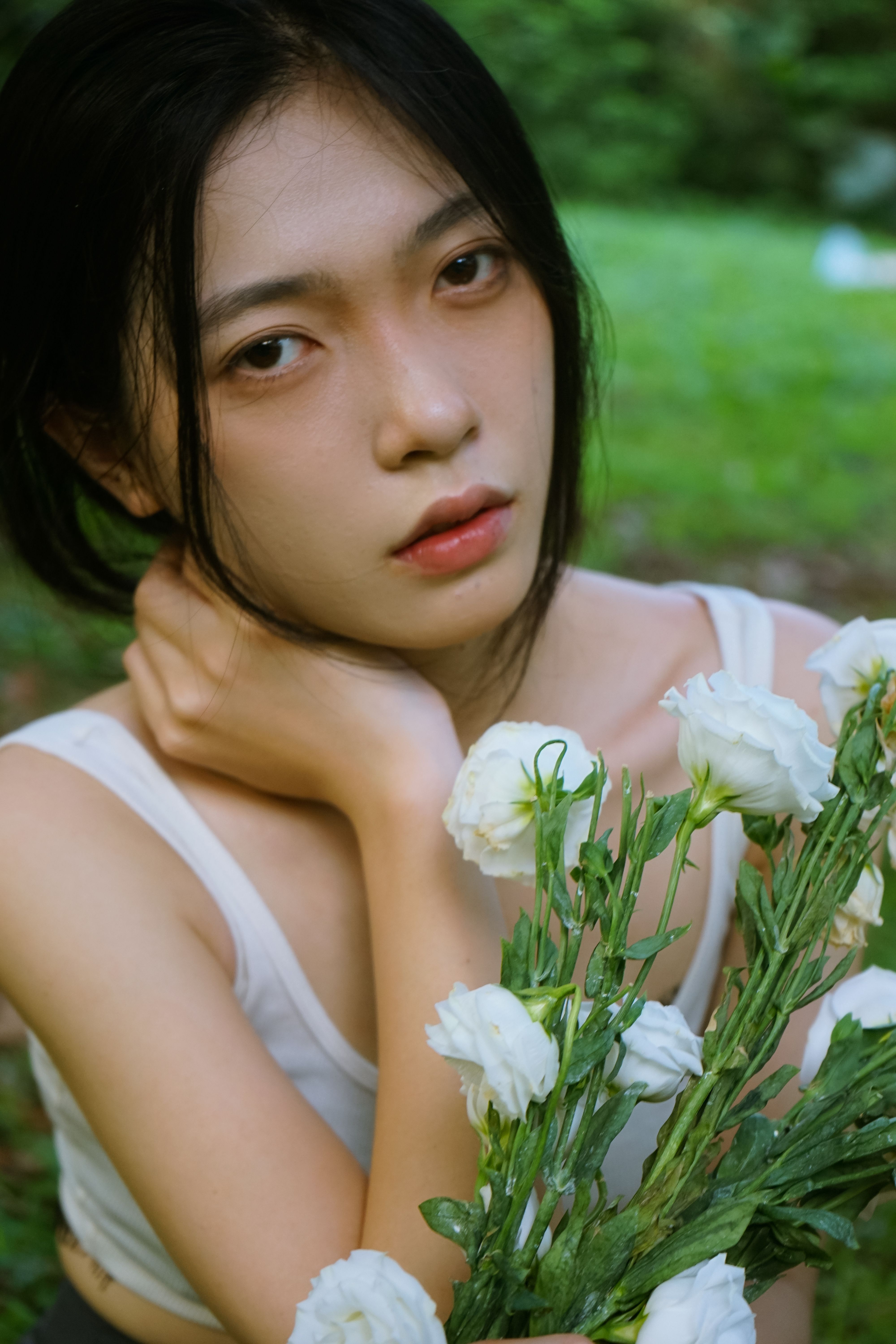 Close-up portrait of a woman holding white flowers outdoors, capturing a serene and natural vibe.