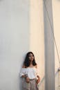 Woman in White Off-shoulder Top Leaning on Wall