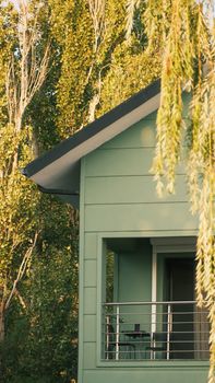 A serene green house with balcony surrounded by lush trees, perfect for a rural getaway.