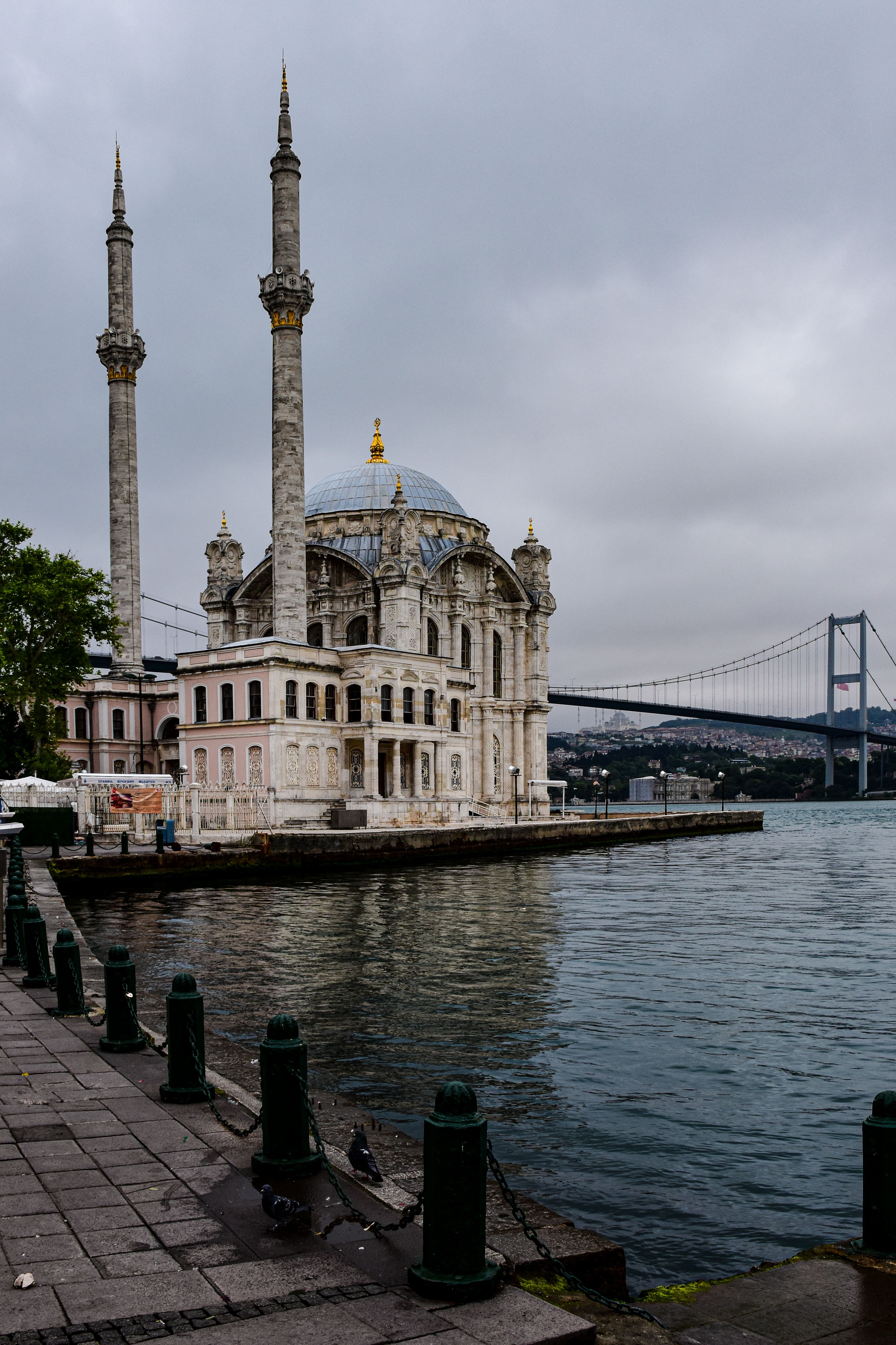 A mosque sits on a body of water near a bridge · Free Stock Photo